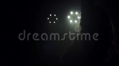 一个舞者在黑暗中在白色聚光灯下跳钢管舞。